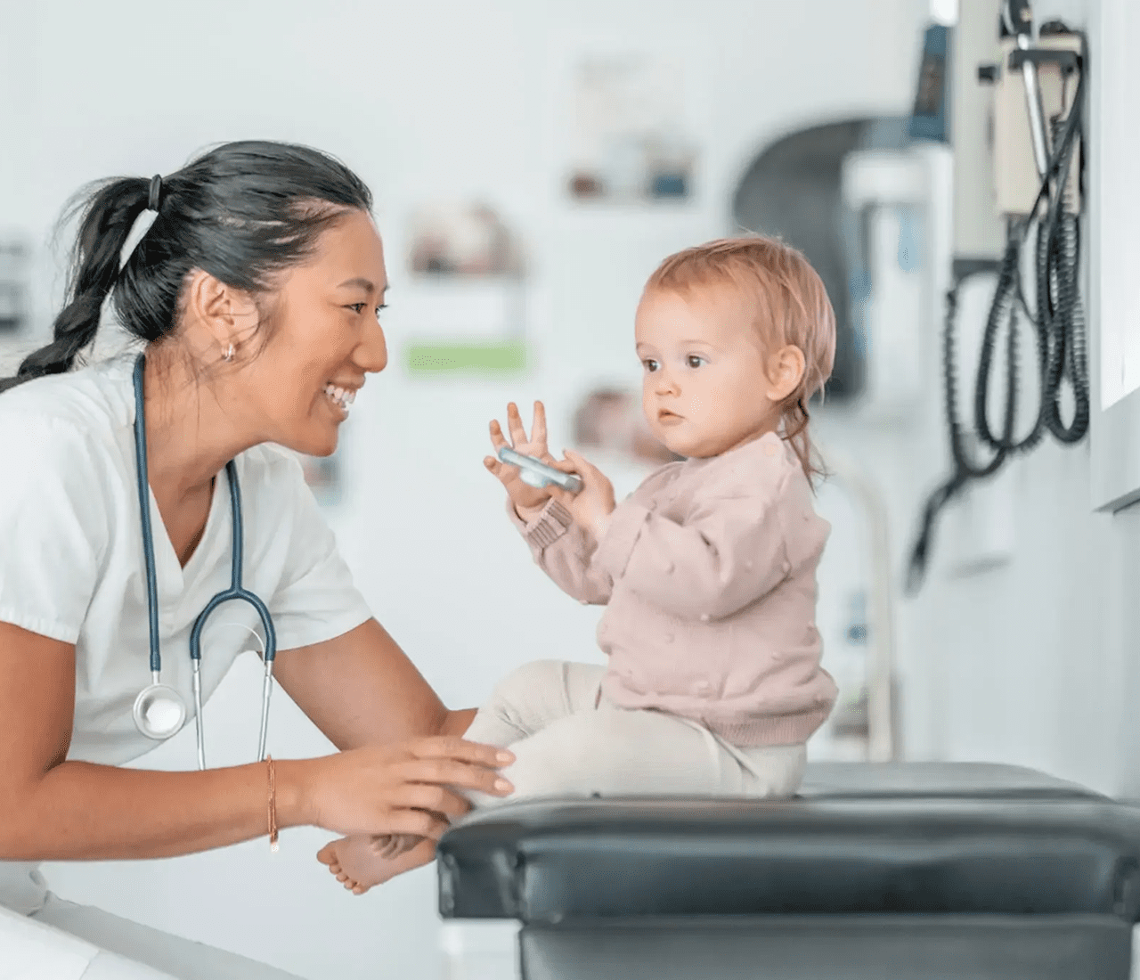 Pediatrician engaging happily with a toddler during a check-up.