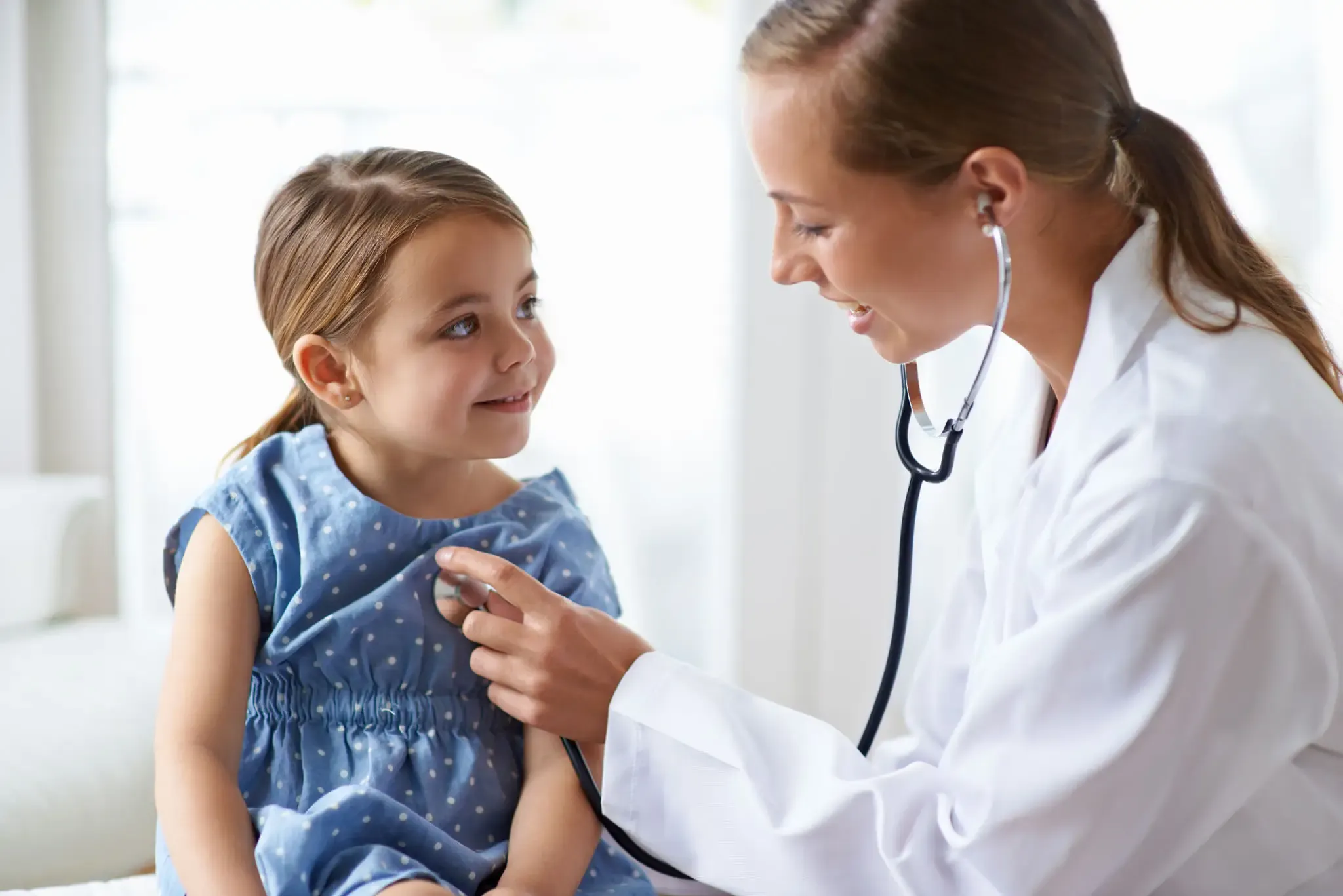 Doctor using stethoscope to check a little girl's heartbeat.